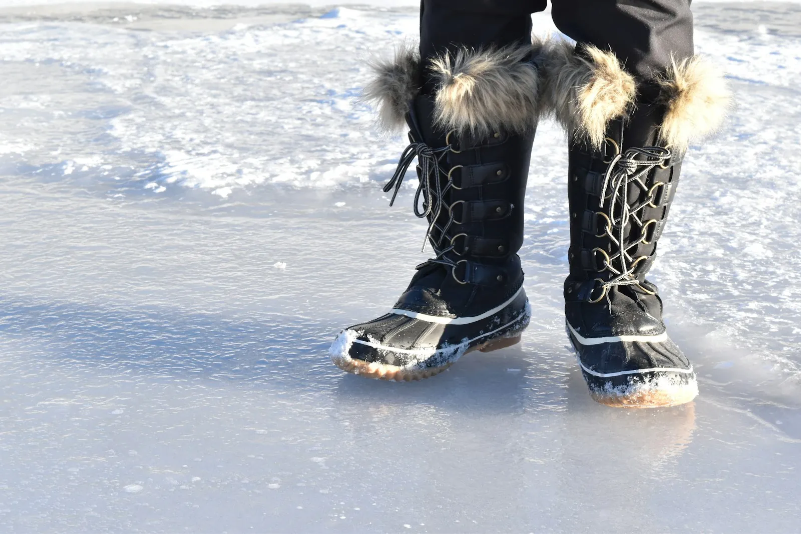 Lace-up snow boots with fur trim standing on ice